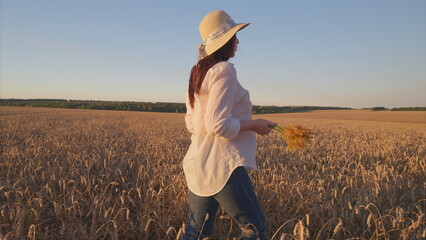 A beautiful woman walking gracefully in a golden wheat field during a stunning sunset