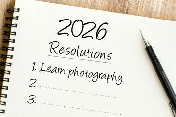 Handwritten 2026 Resolutions list in a spiral notebook with Learn photography as the first goal and a pen.