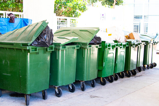 Old rubbish bin large size garbage square shape green with flip cover arranged in same pattern. Old dirty trash green cans plastic. Waste collection equipment in park. Protect environment.