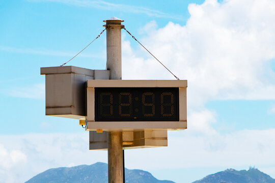 Digital clock time LED red number on black digital electric at Time 12.50 PM. on white signal tower dial with sky and white clouds background. Time symbol concept for celebrating New Year. - Powered by Adobe