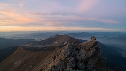 Fototapeta premium Rocky Mountain Ridge Stretches Across Horizon at Pastel Sunrise Sky