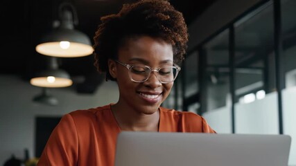 Smiling African American business executive working on a laptop in a modern office, concept for corporate productivity, professional success and digital technology