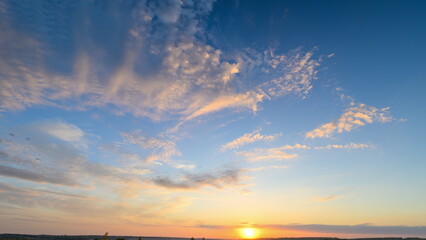 Dawn breaks with vibrant sky, Sunrise paints broad sky in colors, Beautiful dawn over level land with striking highaltitude cloud formations and serene ambiance © beholdereye