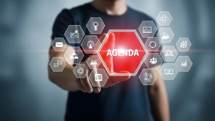 A person interacting with a futuristic interface displaying the word agenda in a red hexagon