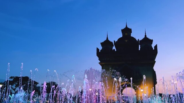 Laos, October 15, 2025: A light and music fountain on the square on the east side of the Patousai Triumphal Arch in Vientiane. A war memorial. Five towers and four passages. Patuxai at night. 4K
