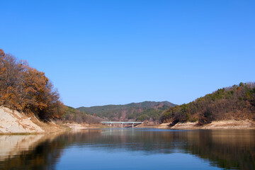 Obraz premium Blue sky, calm river, and autumn mountain