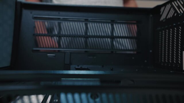 A man manually tightens a standoff inside the PC case in preparation for motherboard installation. Close-up focusing on the hand and threaded mount