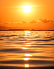 Golden sunset reflecting on tranquil water, mountains in the distance
