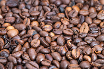 Macro dense roasted coffee beans arranged in uniform pile, deep dark tones and subtle sheen, ideal for wholesale packaging, supply catalogs and background textures