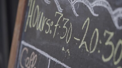 Cafe hours displayed on chalkboard at local cafe