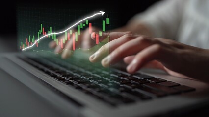 A close-up view of hands typing on a laptop keyboard with a financial graph overlay, illustrating growth and market trends in a digital trading context. Copula