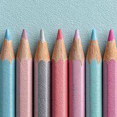 A close up overhead view of seven glitter covered colored pencils in shades of blue pink and silver arranged in a row on a pale blue textured surface.