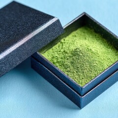 Close up of a dark blue glitter box revealing finely ground bright green matcha powder.