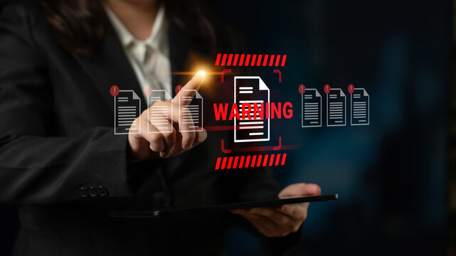 A business professional uses a tablet to interact with a holographic warning notification about important documents, highlighting the significance of data security in modern workplaces. Gantry - Powered by Adobe