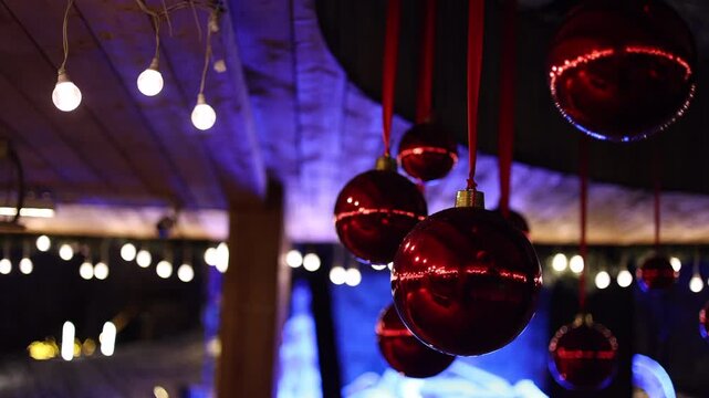 Red Christmas balls hanging on a veranda outdoors, festive holiday decorations. Traditional and cheerful New Year ornaments creating a bright, seasonal atmosphere