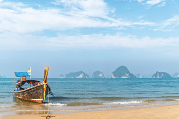 Traditional Thai longtail boat anchored on a peaceful tropical beach with Hong Island blue lagoon background, krabi, Thailand