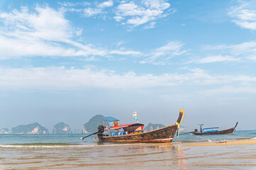 Traditional Thai longtail boat anchored on a peaceful tropical beach with Hong Island blue lagoon background, krabi, Thailand