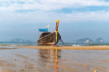Traditional Thai longtail boat anchored on a peaceful tropical beach with Hong Island blue lagoon background, krabi, Thailand