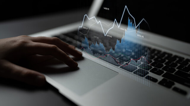 A business professional analyzes financial data displayed on a laptop, featuring sleek graphics that represent market trends and insights, embodying modern analytics. Scalp - Powered by Adobe