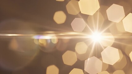 Golden Light Flares and Bokeh - This video shows a radiant burst of golden light with a strong lens flare. Out-of-focus hexagonal bokeh shapes create a soft, warm background. - Powered by Adobe
