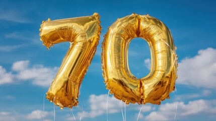 Large gold balloons display the number 70 against a bright blue sky with some clouds during a celebration event