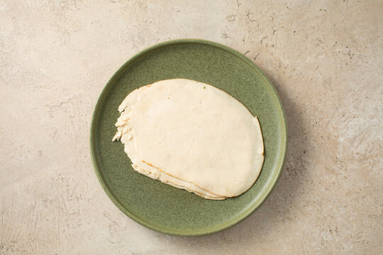 A top down view of a plate of chicken breast deli slices.