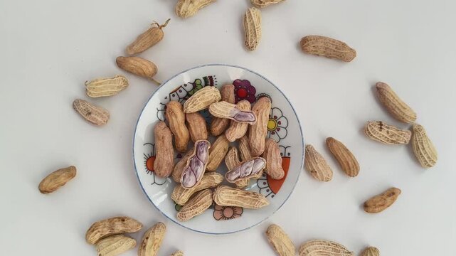 Boiled peanuts served on a plate against. peanuts on a white background.
