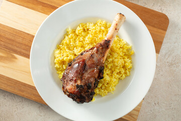 A top down view of a plate of lamb shank and yellow rice.