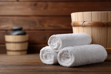 Rolled white towels and wooden bucket in a sauna setting.
