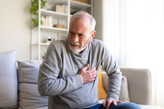 Senior man suffering heart attack on sofa at home