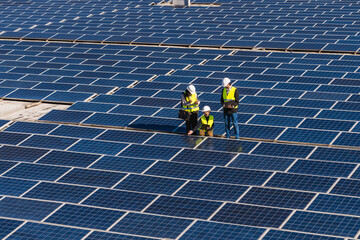 Technical team of solar engineers reviewing photovoltaic panels at a large power plant, working towards sustainable energy generation