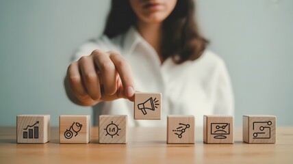 Corporate marketing strategy concept showing entrepreneur arranging megaphone icon with business growth and network symbols on wooden blocks