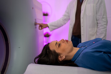Obraz premium Patient lying on a table inside a CT scanner while a doctor operates the machine