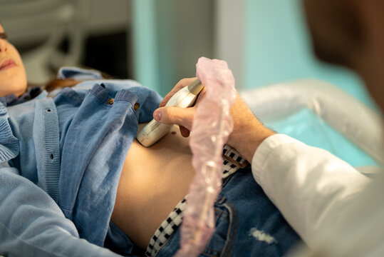 Doctor performing abdominal ultrasound on a young child in a medical examination room