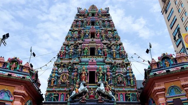 Kuala Lumpur, Malaysia - June 18, 2025: Close-up and facade of the Hindu temple Sri Maha Mariamman Dhevasthanam with prayer flags and sculptures of deities, in Chinatown. 4К
