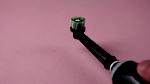 Electric toothbrush on pink background. Modern brush for professional oral hygiene.