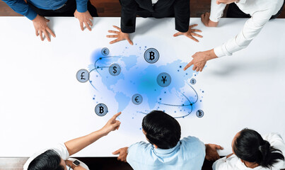 A diverse group of professionals collaborates around a table, analyzing a global financial network represented with various currency symbols on a digital world map. Trope