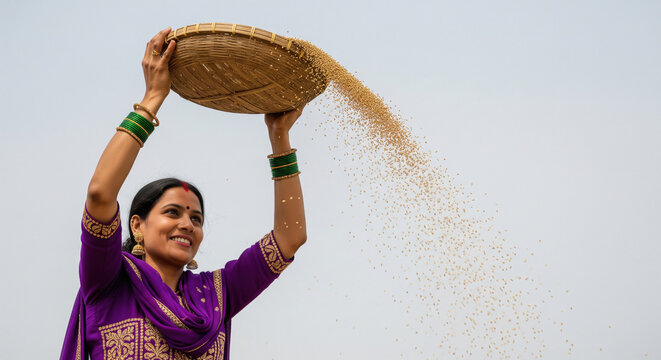 young indian woman winnowing harvested grains with a woven basket at farm