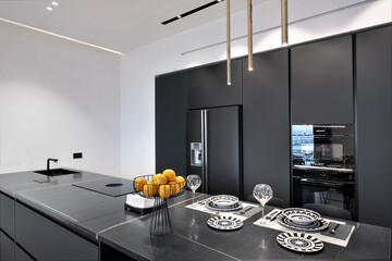 The foreground features a modern marble kitchen island topped with plates and glasses.    