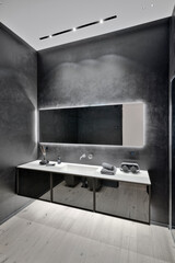 Modern black bathroom interior with parquet flooring and sink cabinet in the foreground.
