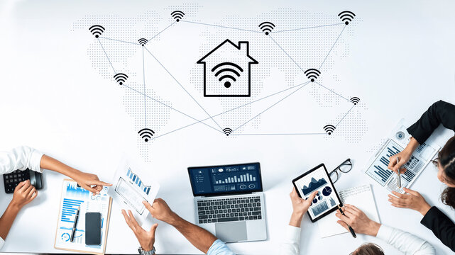 This image captures a group of professionals analyzing smart home technology, showcasing wireless connectivity symbols and data analysis through graphs and charts. Gantry - Powered by Adobe