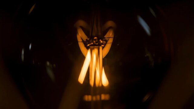 Close-up of a vintage light bulb with intricate filament design, emitting a warm glow against a dark background, symbolizing innovation.