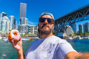 Tourist taking selfie with donut in vancouver harbor