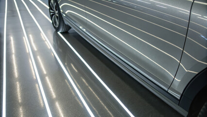 Silver car with sleek design reflecting bright diagonal light streaks on polished floor, creating modern and dynamic atmosphere