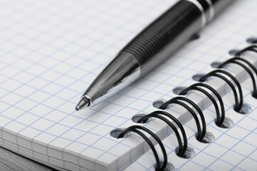 school and office supplies ballpoint pen lying on a notebook