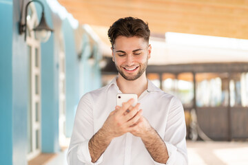 Young handsome man sending a message or email with the mobile