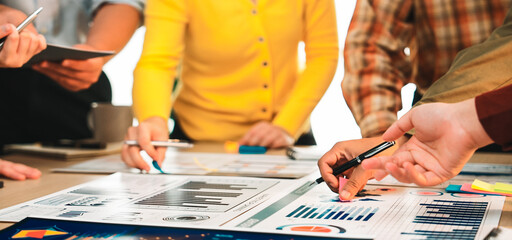 A diverse business team engaged in a collaborative session, analyzing market reports and financial charts on a modern office table, showcasing teamwork and productivity. SACTR