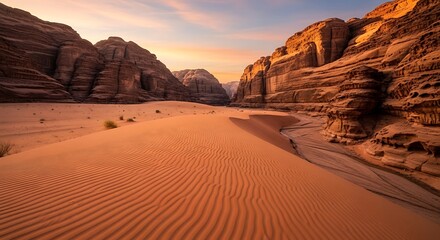 Vast desert landscape with towering sandstone cliffs and rippled sand dunes at sunset.