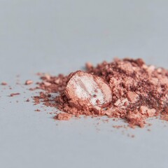 Crumbled, rose-toned makeup powder on light gray surface