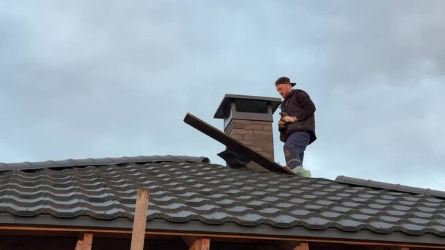 A master stove setter secures a cap on the stove pipe. Heating stove construction.